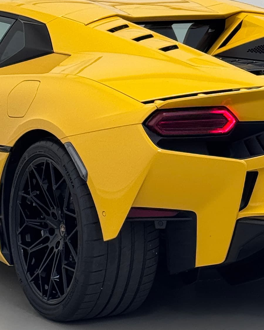 The rear wheel and tail light of a yellow supercar in close detail