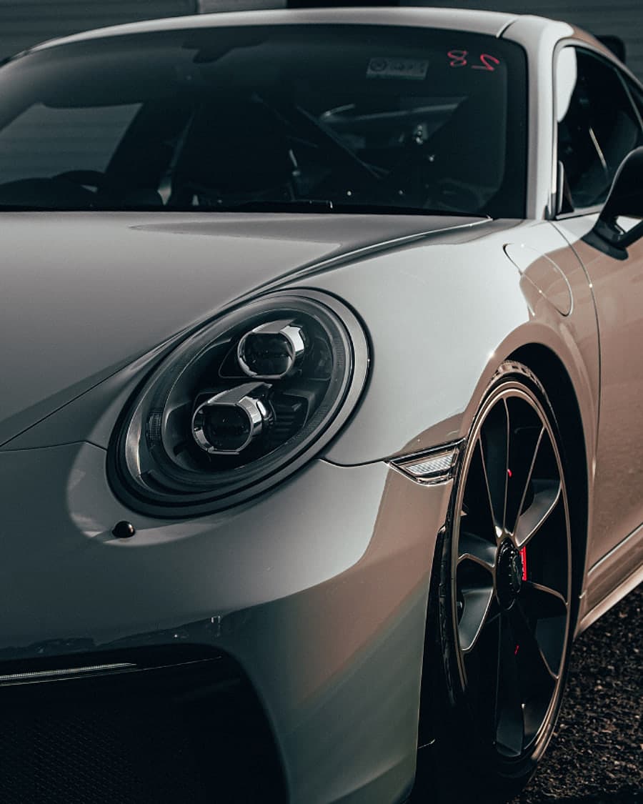 The front of a silver sports car under low garage light